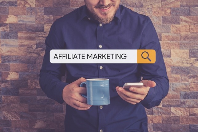 Man searching affiliate marketing on phone with coffee cup in hand